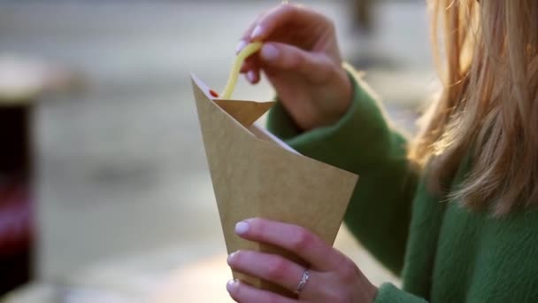 Mujer comiendo papas fritas al aire libre en invierno calle inmersión en ketchup, primer plano — Vídeo de stock