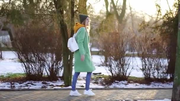 Kvinna gå frikostigt i vinterparken i grön vinterrock — Stockvideo