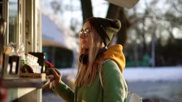 Žena vybírá zboží v pouličním kiosku na zimní procházce, čeká na objednávku — Stock video
