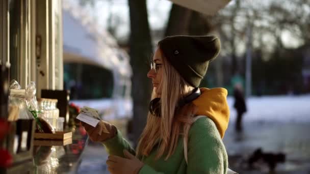 Γυναίκα στο καπέλο παίρνει μια αλλαγή των χρημάτων από το περίπτερο καφέ του δρόμου το χειμώνα — Αρχείο Βίντεο