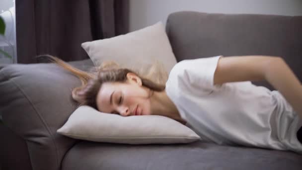Уставшая или скучающая молодая сонная женщина падает на диван — стоковое видео