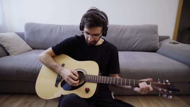 Potret seorang pria dengan gitar bermain dan melihat kamera di ruang tamu — Stok Video