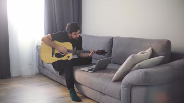 Um jovem toca guitarra através de uma videochamada em um laptop — Vídeo de Stock