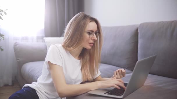 Femme blonde assise sur le sol, paie les achats en ligne avec une carte de crédit et un ordinateur portable — Video
