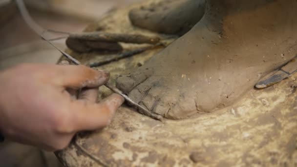 Primer plano de los pies de la estatua de Budas de arcilla, artista trabaja con detalle usando espátula — Vídeo de stock