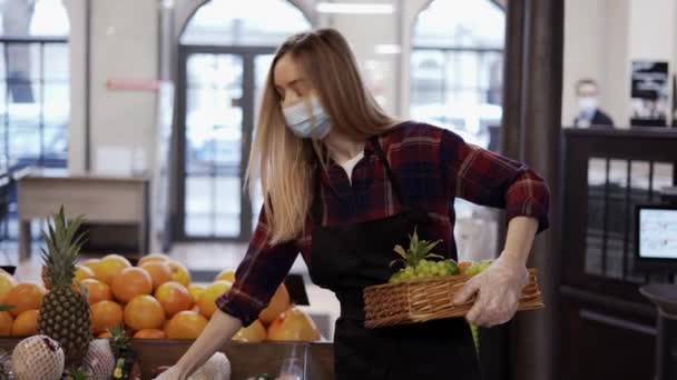 穿着黑色围裙和面罩的女工在超级市场为水果长袜 — 图库视频影像