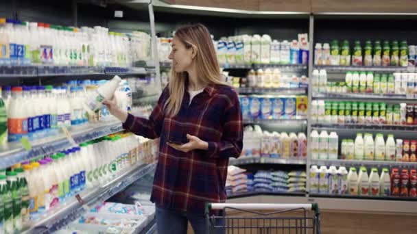 Woman shopping in supermarket using smart phone, checking shopping list — Stock Video