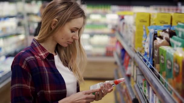 Mujer camina en la tienda y examina las mercancías en los estantes — Vídeos de Stock