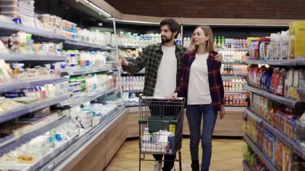 Couple shopping in supermarket with cart, front view — Stock Video