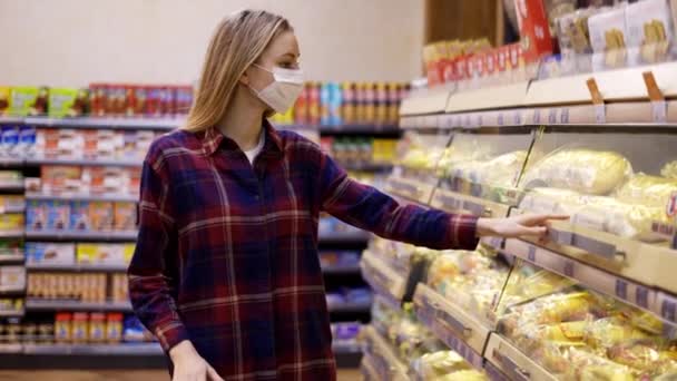 Jeune femme porte un chariot dans le supermarché prendre du pain — Video