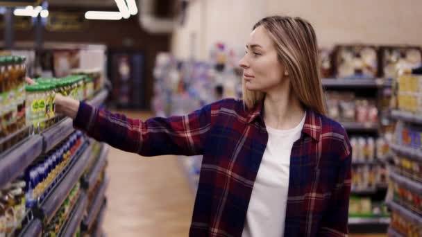 Vrouw koopt eten bij supermarkt of kruidenier met winkelwagentje — Stockvideo