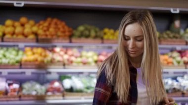 Süpermarkette alışveriş yaparken poz veren pozitif genç kız.