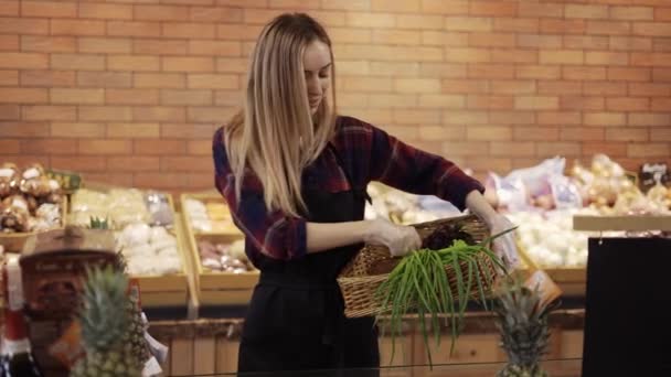 Uśmiechnięty pracownik w czarnym fartuchu organizujący zieleninę w supermarkecie — Wideo stockowe