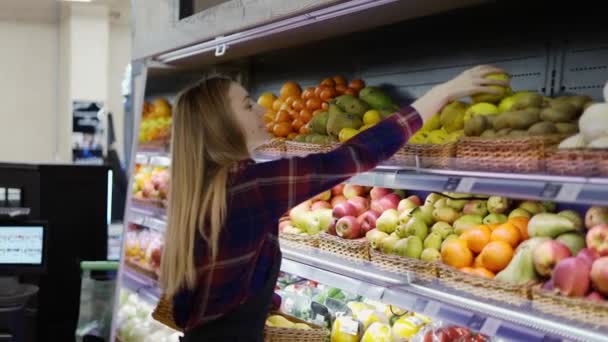 Belle ouvrière en tablier noir arrangeant des citrons au supermarché — Video