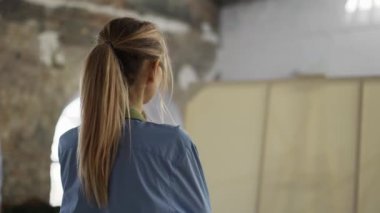 Kadın sanatçı atölye ve genel bakışında sanat eserlerinin önüne yansıyor.