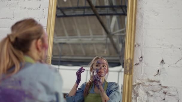 Woman cleaning face from paints in front mirror using napkin — Stock Video