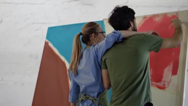 在画室里，年轻夫妇在画布上画画，女人亲吻男人 — 图库视频影像