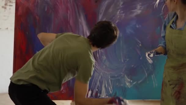 情侣们在工作室里创作抽象绘画杰作，喷涂颜料 — 图库视频影像