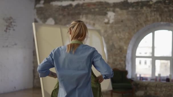 Unrecognizable woman put on apron to start painting in workshop — Stock Video