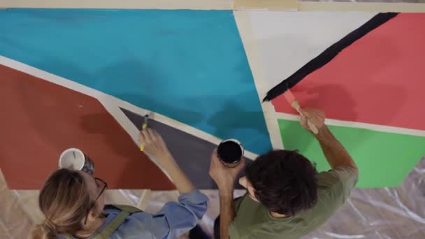 Νεαρό ζευγάρι ζωγραφίζει σε καμβά ζωγραφίζοντας εικόνα στο στούντιο τέχνης και φιλιά, θέα υψηλής γωνίας — Αρχείο Βίντεο