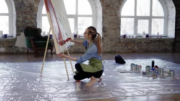 Художник, що працює з великою пензлем і широким полотном у майстерні, стоячи на колінах — стокове відео