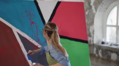 Kadın sanatçı duygusal olarak, pencerenin önündeki stüdyoda soyut resmin şaheserini yaratıyor.