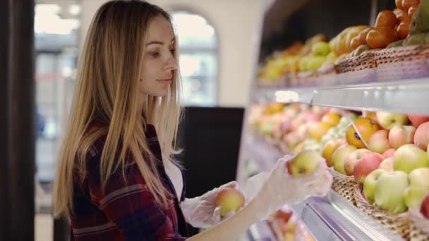 Mujer en guante recoge frutas manzanas en cesta en el supermercado — Vídeos de Stock