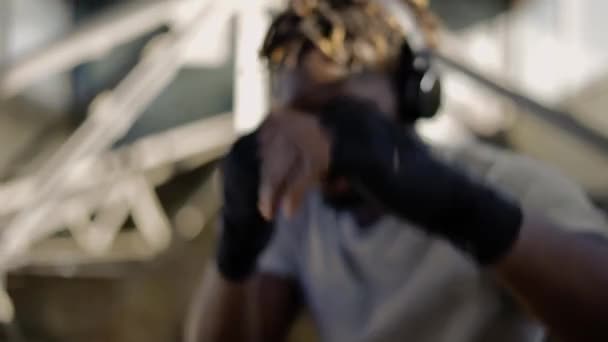 Joven boxeador afroamericano practicando boxeo de sombras alrededor de las estructuras metálicas, de cerca — Vídeo de stock