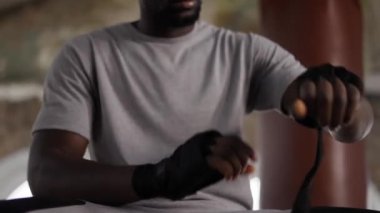 Erkek boksör elleri siyah bandajla sarıp kapatıyor.