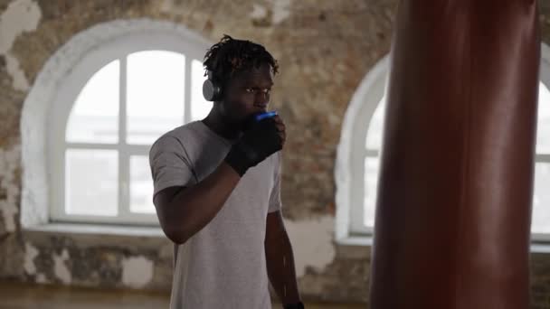 Boxeador masculino afroamericano tomando un descanso para beber de una taza de plástico, en cámara lenta — Vídeo de stock