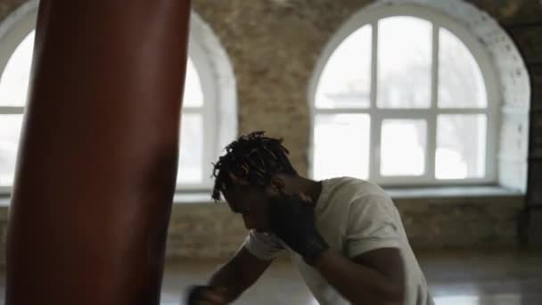 Афро-американский боксер бьет тяжелую сумку агрессивно, кричит — стоковое видео