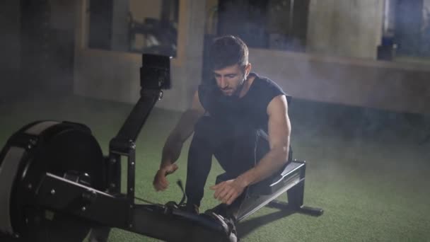 Yakışıklı sporcu spor salonunda kürek makinesiyle çalışıyor. — Stok video