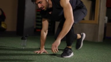Su içen adam, karanlık spor salonunda yer şınav çektikten sonra dinleniyor.