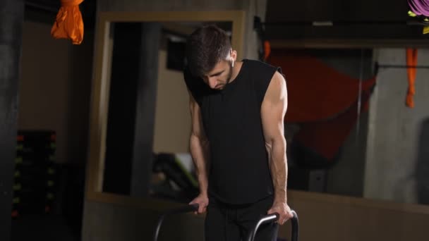 Sportowiec robi poziome ćwiczenia bar, podciąga się w ciemnej siłowni — Wideo stockowe