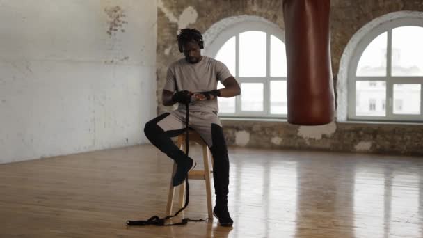 Afro american boxer is wrapping hands with black bandage — Stock Video