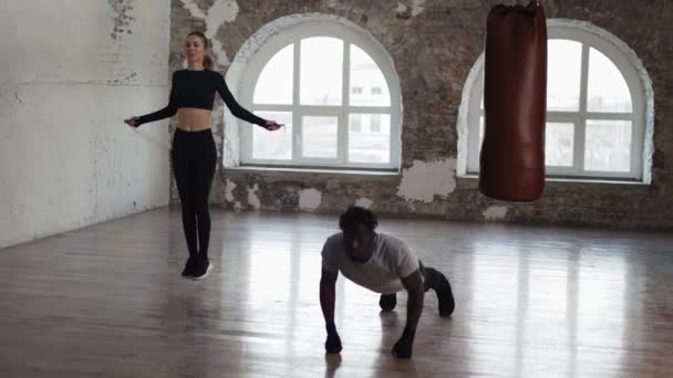 Entraîneur musculaire personnel travaillant pendant qu'elle s'entraîne avec corde sautante — Video