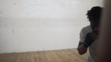 Kendine güvenen boksör spor salonunda kum torbasını yumrukluyor.