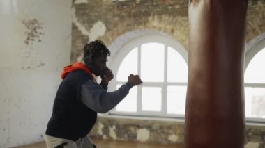 Afro-Amerikan erkek boksör. Parlak salonda kulaklıkla gölge boksu yapıyor.