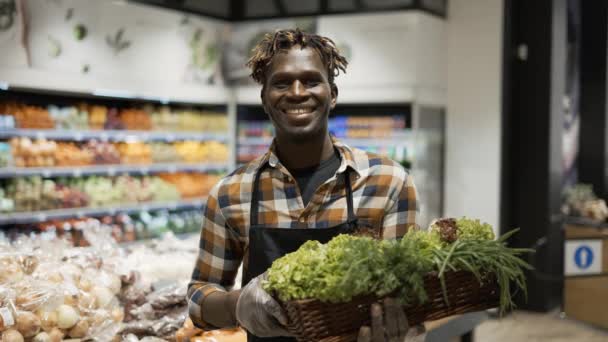 Portré mosolygós munkás a boltban egy kosár zöldséggel