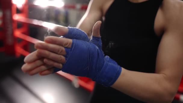 Woman rubs powder on her hands wrapped in boxing tapes on boxing ring — Stock Video