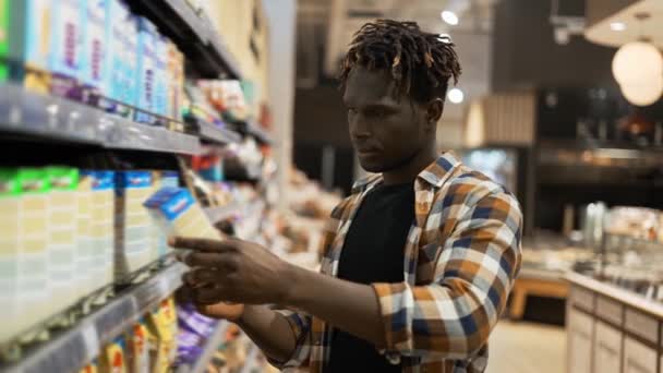 Стильний афроамериканський хлопець вибирає товари в продуктовому магазині — стокове відео