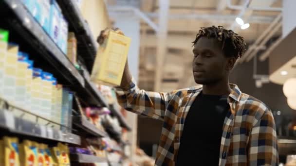 Африканський американець вибирає продукти в продуктовому магазині і кладе їх на візок. — стокове відео