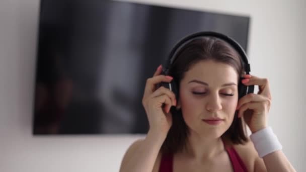 Mulher colocando música em fones de ouvido e aquecimento inicial — Vídeo de Stock