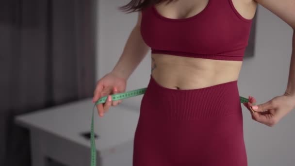 身穿红色运动服的体形瘦小的女性测量腰围 — 图库视频影像