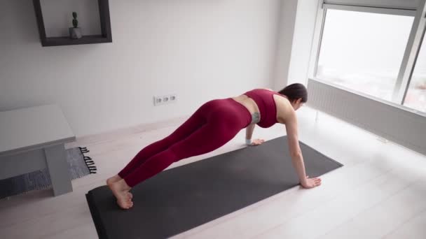 Fiatal sportos nő push-up gyakorlatokat csinál az ablakban. — Stock videók