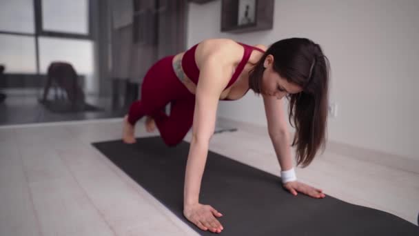 Жінка робить дошку згинаючи ноги вправи в динаміці вдома — стокове відео