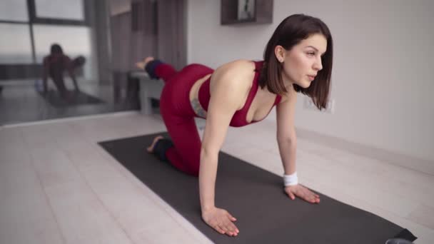 Vrouw op mat oefenen ezel kick oefening met enkel gewicht, het verhogen van een been omhoog — Stockvideo