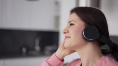 Mutfakta kulaklıkla dans eden gülümseyen kadın portresi.