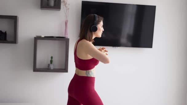 Vrouw zet muziek op in hoofdtelefoon en begint benen te strekken — Stockvideo