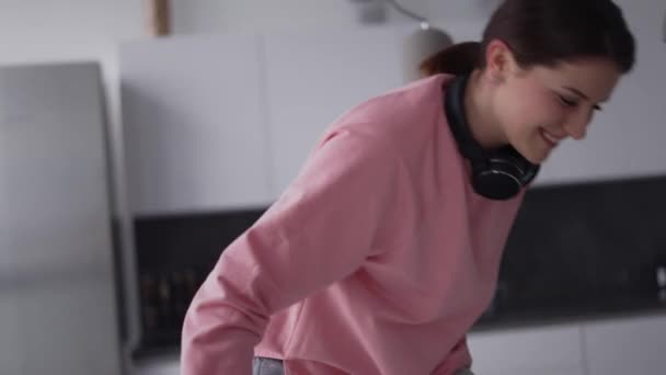 Leende flicka som har roligt i köket, faller på soffan — Stockvideo